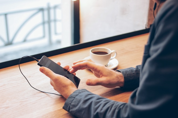 Hombre que usa el teléfono móvil con auriculares en el café