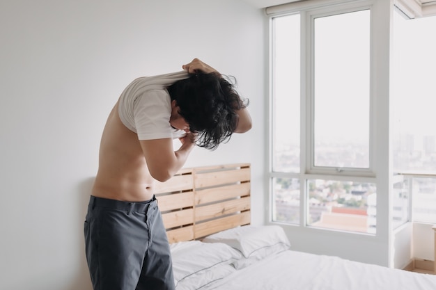 El hombre se quita la camiseta en el apartamento de su habitación