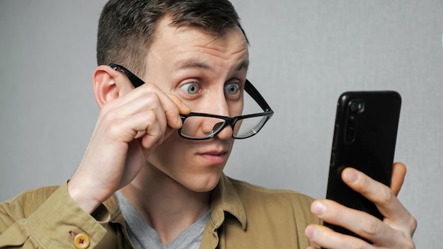 Foto el hombre se quita las gafas después de leer las noticias en el teléfono móvil