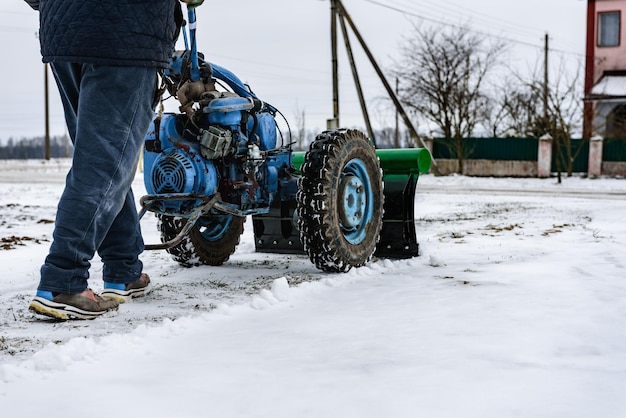 Foto un hombre quita la nieve de su patio con la ayuda de un cultivador de motocicleta