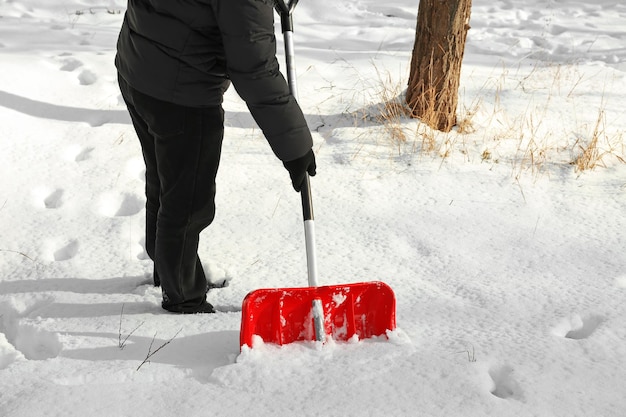 Hombre quitando nieve con pala roja