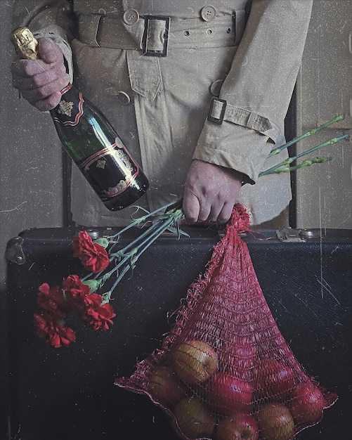 Foto el hombre con un ramo de claveles rojos, una bolsa de manzanas y una botella de champán regresó a casa.