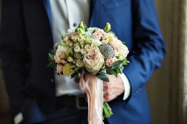 Hombre con ramo de novia en las manos novio preparándose en la mañana antes de la ceremonia de boda