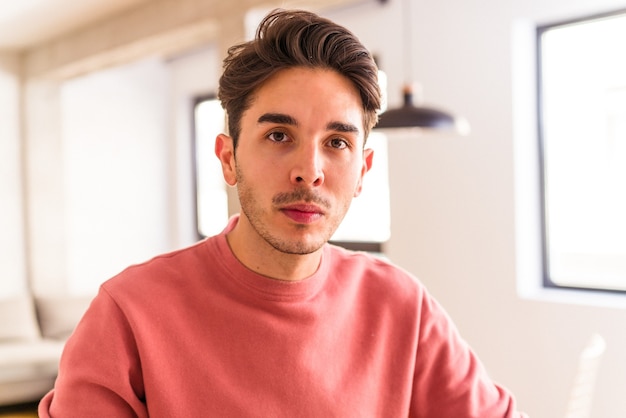 Hombre de raza mixta joven comiendo croissant en una cocina en la mañana