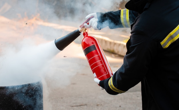 Un hombre realiza ejercicios con un extintor de incendios. Concepto de extinción de incendios. Incidente de emergencia de incendio