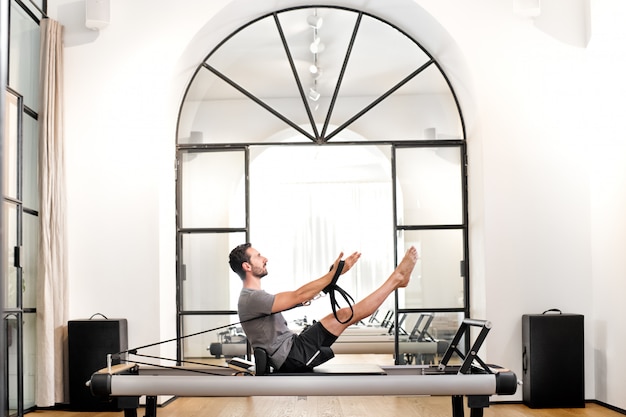 Hombre realizando ejercicios de pilates teaser en un gimnasio