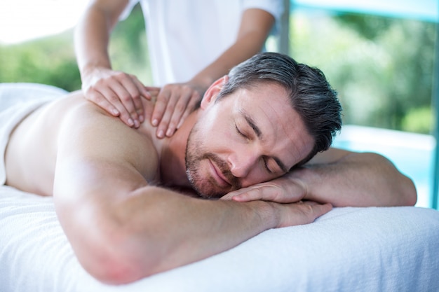 Foto hombre recibiendo masaje de espalda de masajista