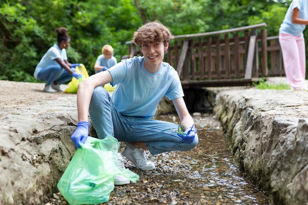 Hombre recogiendo a mano recolectando basura pajitas de plástico basura del río en el parque Día mundial del medio ambienteConcepto de medio ambiente
