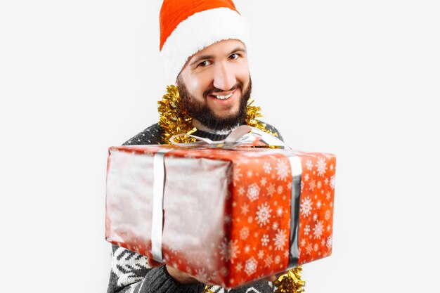 Un hombre con un regalo de Navidad en sus manos en el estudio sobre un fondo blanco regalo closeup da un regalo de Navidad