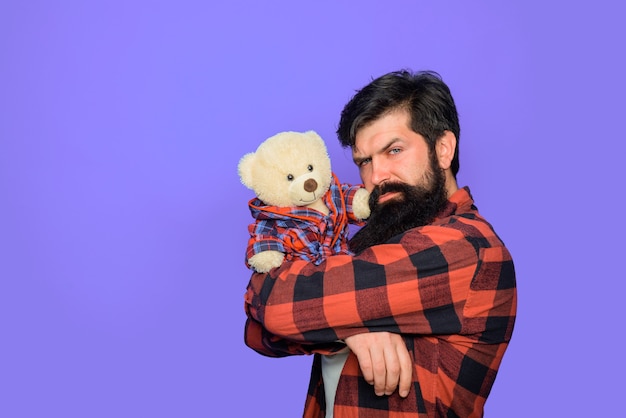 Hombre con regalo de oso de peluche esponjoso y presente hombre serio mantenga vacaciones de juguete de peluche de oso de peluche