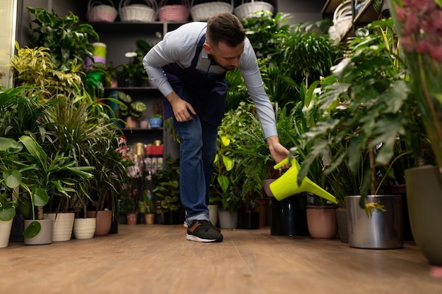 Hombre regando plantas en macetas de una regadera