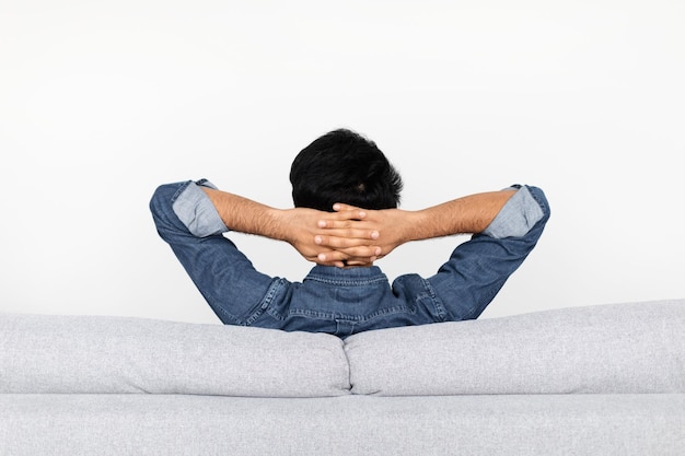 Hombre relajado descansando en el sofá en casa vista posterior