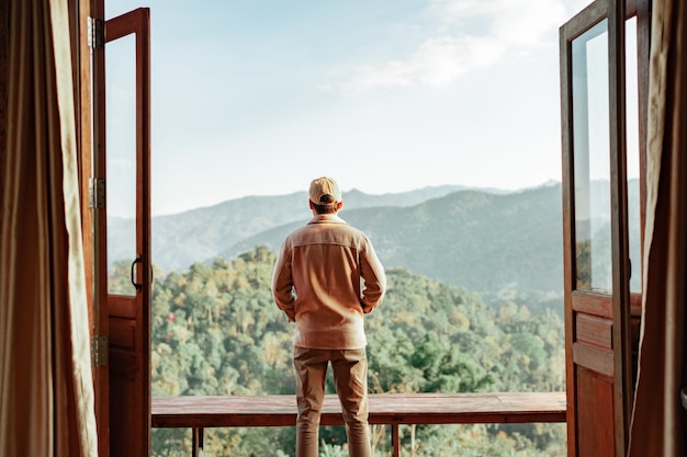 Hombre relajándose en el balcón que puede ver la vista a la montaña y la niebla matutina