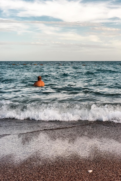 Hombre relajándose en el mar con playa de arena