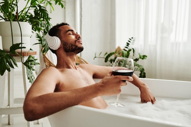 hombre, relajante, en, baño, con, copa de vino