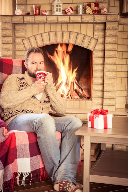 Hombre relajante en casa junto a la chimenea. Concepto de vacaciones de invierno