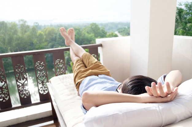 Hombre relajante en su silla y disfrutar de la vista desde la terraza.