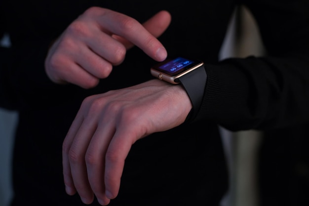 Hombre con reloj inteligente vestido de negro. Cerca de manos.