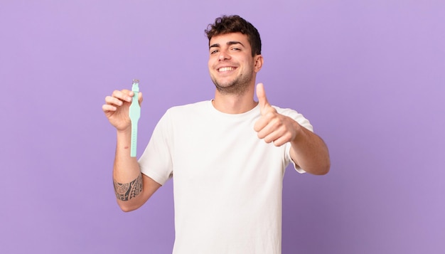 Hombre con un reloj que se siente orgulloso, despreocupado, seguro y feliz, sonriendo positivamente con los pulgares hacia arriba