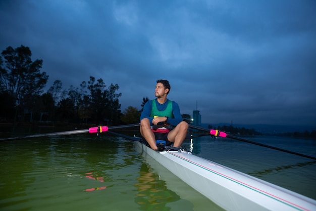 Foto hombre remando en el retrato del lago y cielo nublado