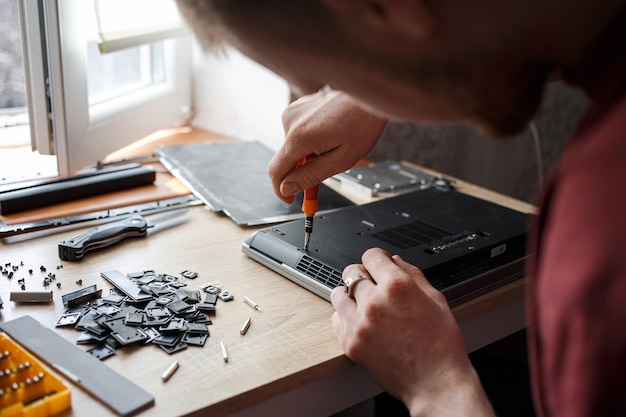 El hombre repara la computadora portátil por sí mismo reparación de computadoras