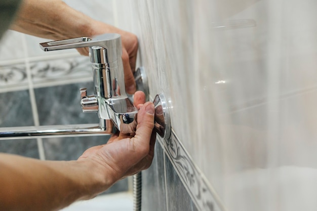 un hombre repara un grifo en el baño