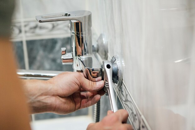 un hombre repara un grifo en el baño