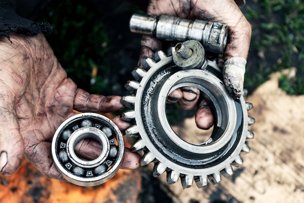 El hombre repara el motor del tractor, maquinaria agrícola. Rodamientos en manos sucias.