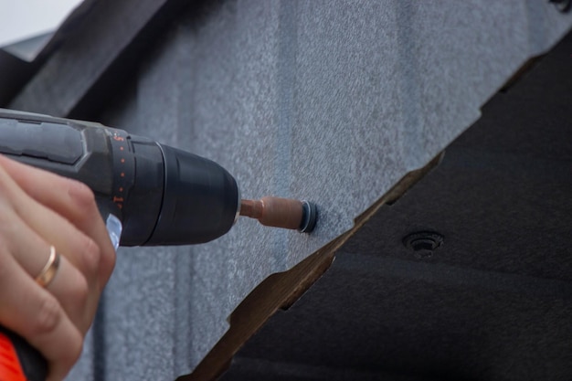 Un hombre repara el techo aprieta el tornillo automático con un destornillador enfoque selectivo