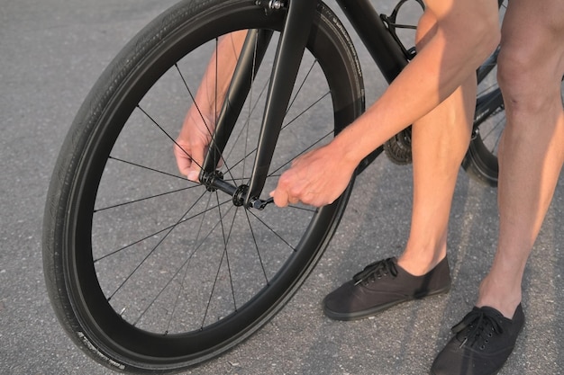 hombre reparando una bicicleta, sosteniendo un excéntrico en el cubo y atornillando una rueda de carbono