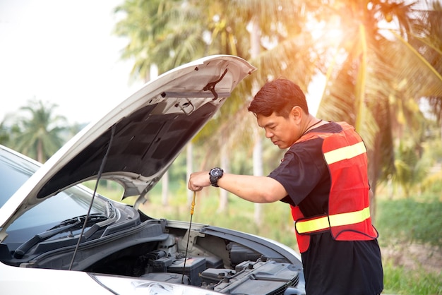 Hombre reparando un coche contra los árboles