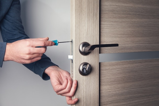 Hombre reparando la manija de la puerta con un destornillador