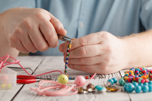 Hombre reparando o creando joyas de plata con alicates