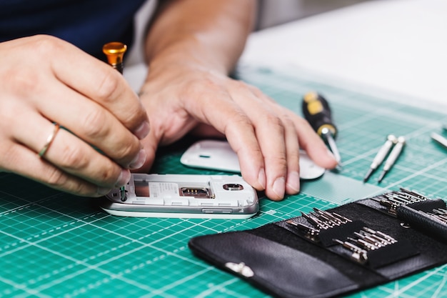 Hombre reparando smartphone roto, foto de cerca.