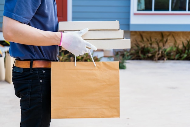 Foto un hombre de reparto sostiene una caja de mercancías y comida para un cliente frente a la casa