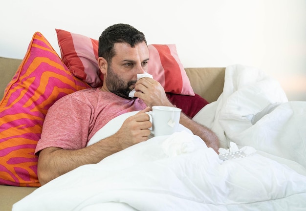 Hombre con resfriado y positivo por coronavirus, bebiendo un té.