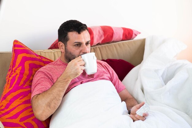 Hombre con resfriado y positivo por coronavirus, bebiendo un té.