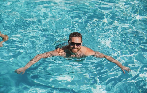 Hombre de resort de piscina de verano en chico de vacaciones de verano en gafas de sol relajándose en la piscina