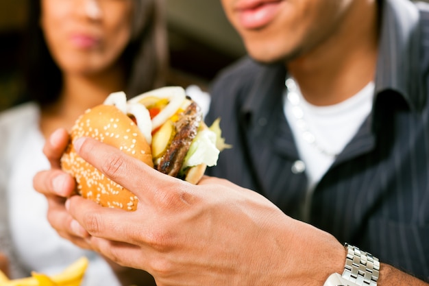 Foto hombre en un restaurante comiendo hamburguesas