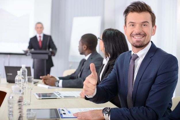 Hombre en una reunión de negocios que muestra los pulgares para arriba.