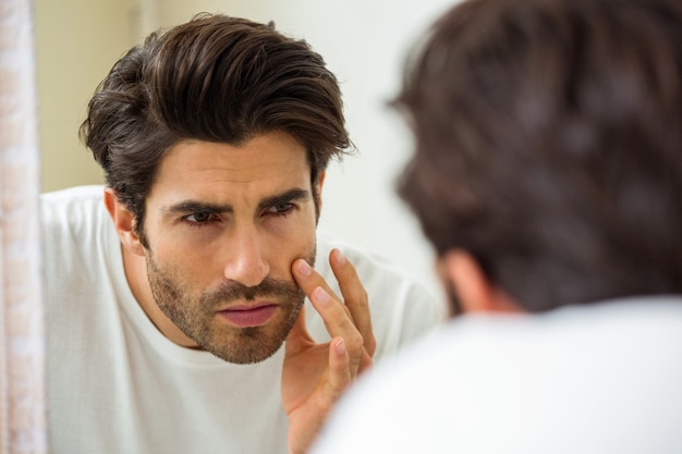 Hombre revisando su piel en el baño.