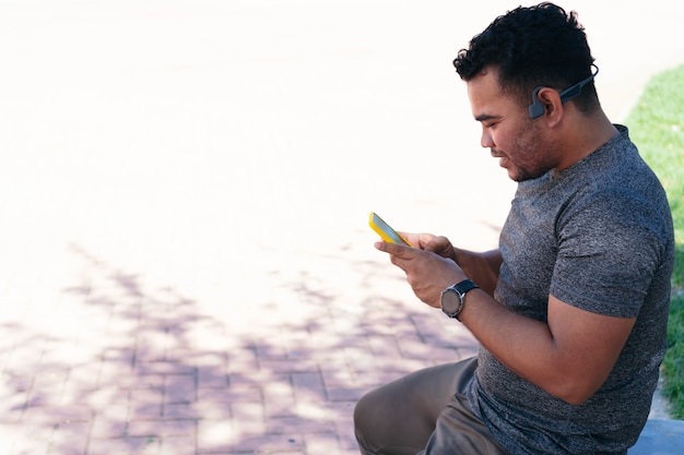 Hombre revisando su teléfono celular mientras entrena al aire libre