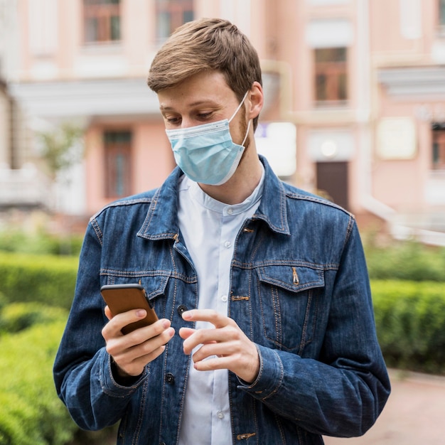 Foto hombre revisando su teléfono mientras usa una mascarilla