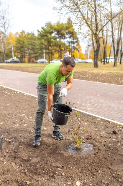 Un hombre riega un árbol recién plantado como parte de un programa de ecologización de la ciudad