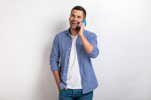 Hombre riendo hablando con un teléfono inteligente y mirando hacia arriba