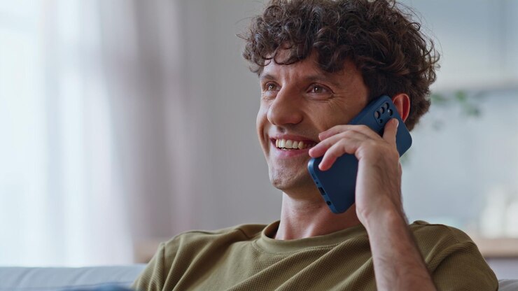 Foto hombre riendo hablando por teléfono móvil en el sofá en la casa de fin de semana sintiéndose relajado de cerca
