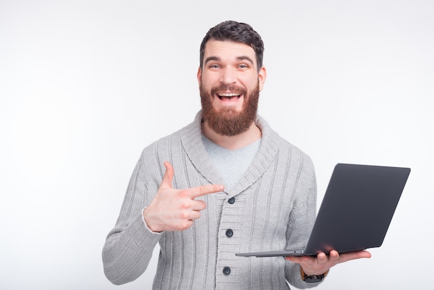 El hombre de risa está señalando en su computadora portátil que muestra algo en el fondo blanco.