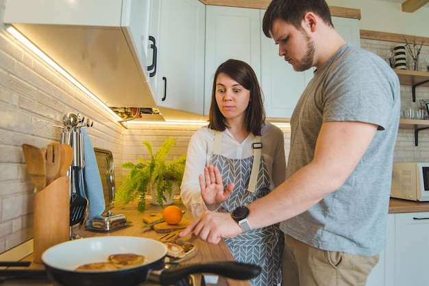 Foto el hombre roba comida mientras la mujer prepara el desayuno