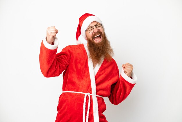 Hombre rojizo disfrazado de Papá Noel aislado en blanco celebrando una victoria