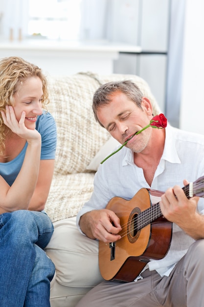 Hombre romántico tocando la guitarra para su esposa en casa